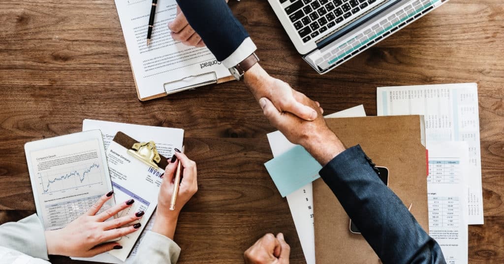 fiduciary shaking hands with couple after reviewing their finances