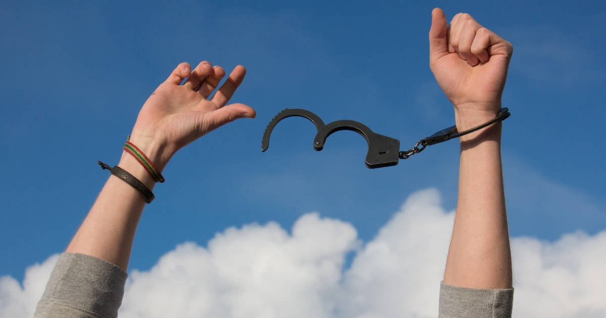 hands raised with handcuffs coming off as symbol of breaking the debt cycle