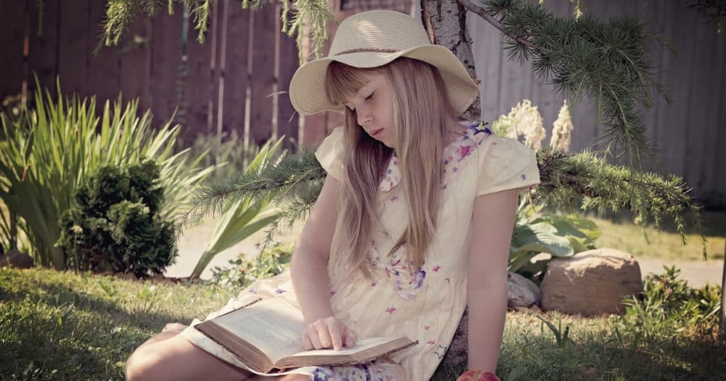 middle school girl sitting outside reading a money book