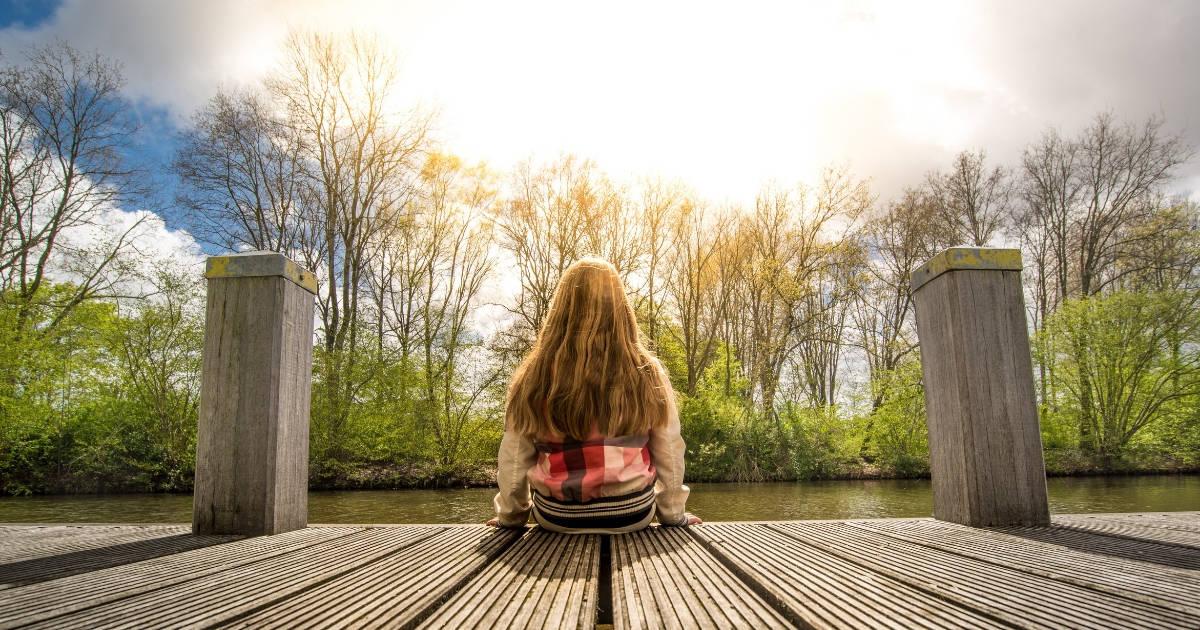 woman sitting on dock overlooking lake contemplating Roth or Traditional IRA