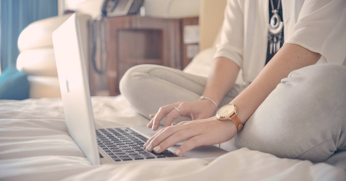 woman sitting on her bed with laptop working from home