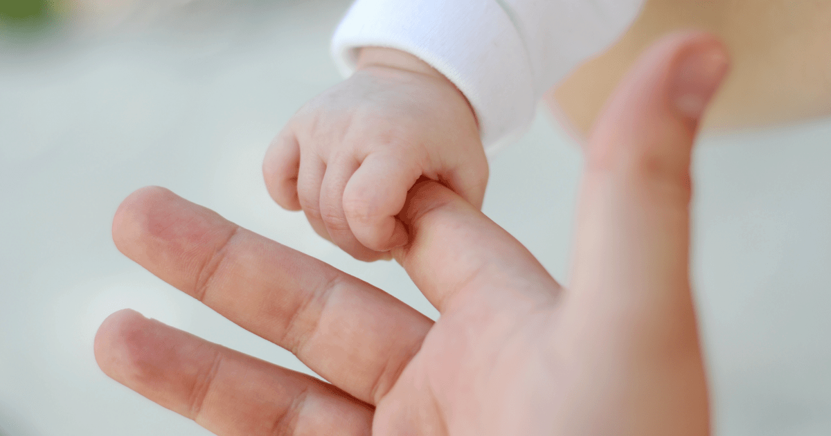 Parent holding baby's small hand