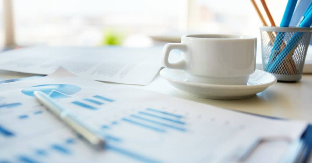 Paperwork on desk with coffee cup considering types of annuities