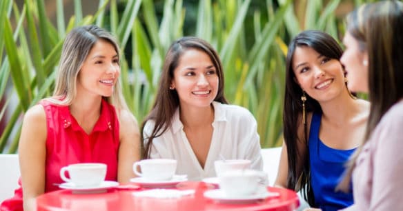 group of friends at book club sitting around a red table with coffee