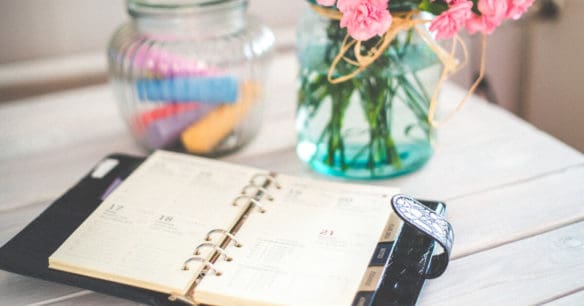 flowers on desk with ring bound planner sitting on desk to schedule book club