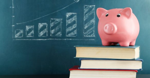 Piggy bank on books with blackboard - Should you refinance your student loans?