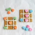 valentine's day inspired tic tac toe board made with icing on graham cracker with conversation hearts for pieces 