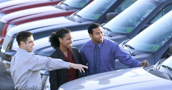 couple wanting to buy a car looking at vehicles with a salesman on a car lot