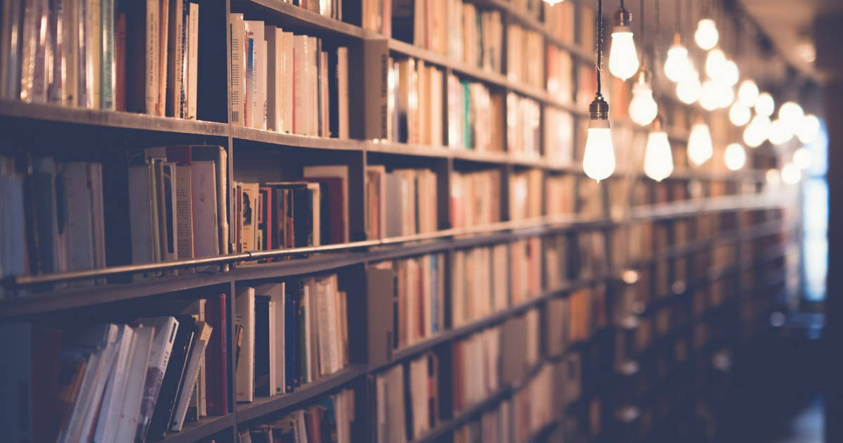 Shelves of books in a library with hanging rustic lights above