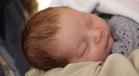 infant wrapped in grey blanket sleeping