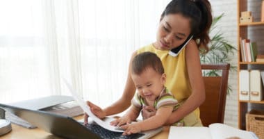 mom returning to work after maternity leave working on phone and computer with baby in lap