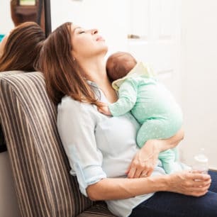 mom resting her eyes in a chair with baby on her chest after returning from maternity leave