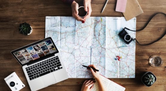 map on desk with computer and notebook planning a travel hacking trip